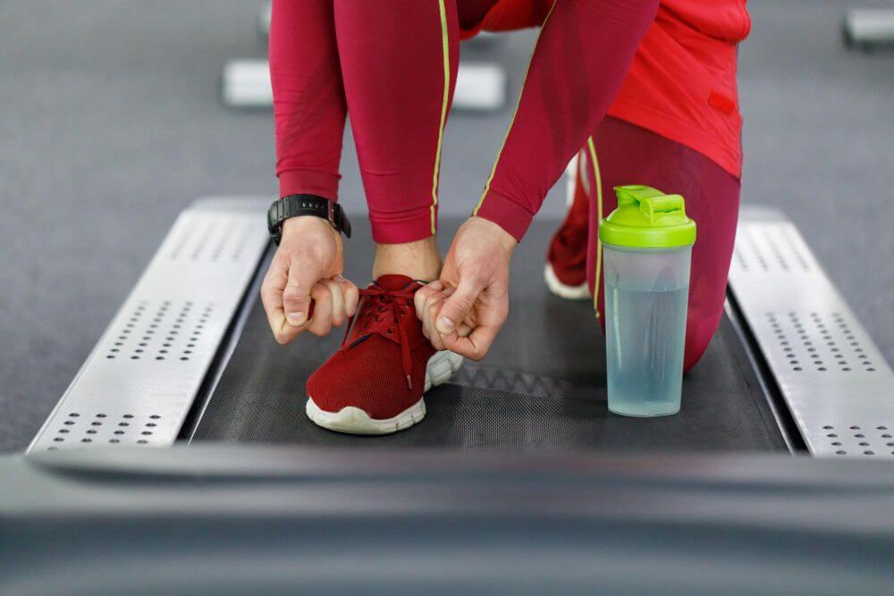A person in red preparing to run on a treadmill