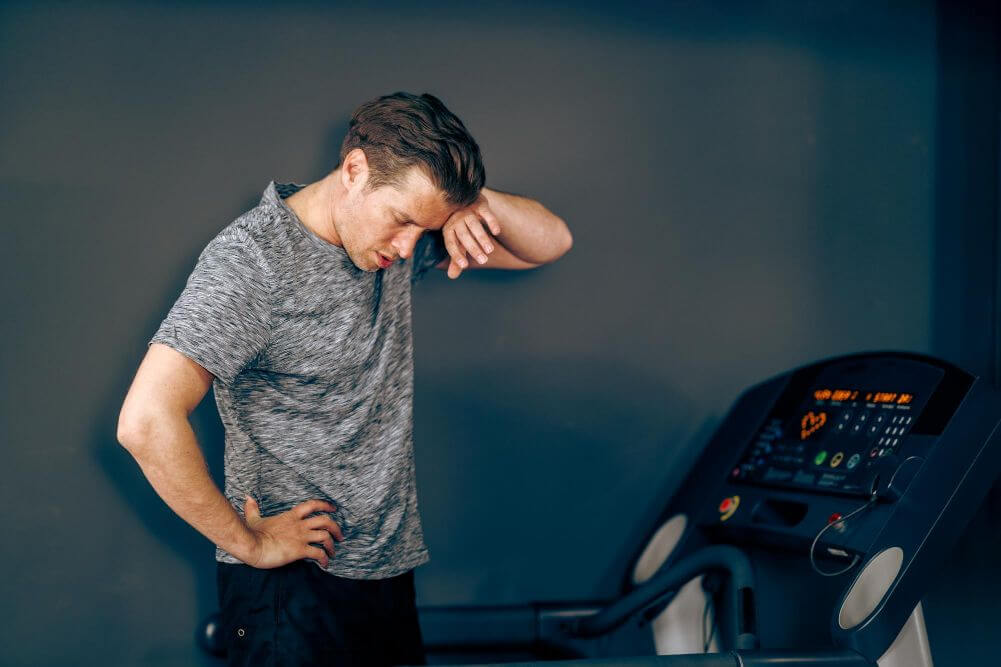 One person looks tired beside a treadmill