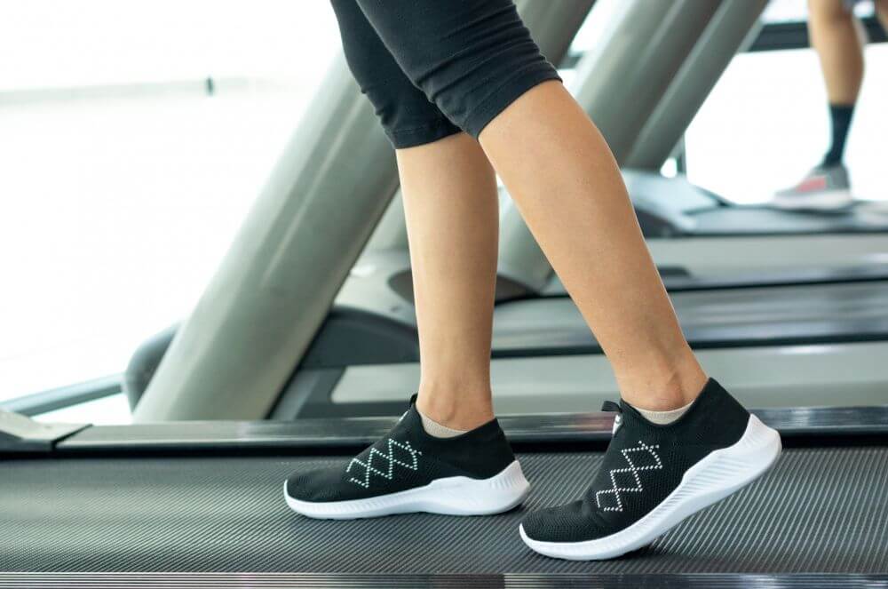A woman on a treadmill with black running shoes
