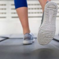 A woman running on a treadmill wearing trail shoes
